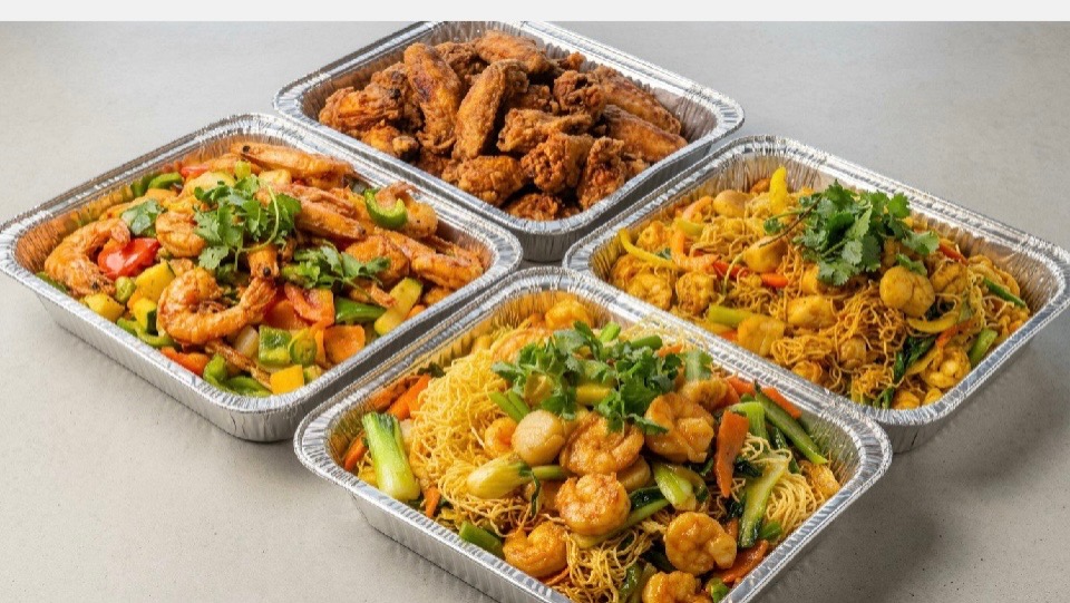 Catering trays with wings, shrimp, noodles and vegetables at Eggymon Kitchen in Alpharetta